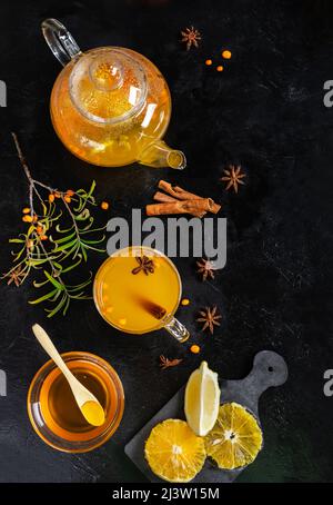 Sanddorn-Getränk in Teekannen und Becher mit Honig, Orange, Zitrone, Zimt. Anissterne Stockfoto