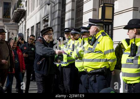 London, Großbritannien. 09. April 2022. Vor dem Hauptsitz von BP wird ein Protestler gesehen, der der MET-Polizei Flugblatt überreicht. Die Protestgruppe „Extinction Rebellion“ ruft zu einer neuen Runde von Protesten über die Osterferien auf, um die Beendigung der Nutzung fossiler Brennstoffe voranzutreiben. Die Demonstranten fordern ein sofortiges Ende aller neuen Investitionen in fossile Brennstoffe, da die Abhängigkeit von fossilen Brennstoffen den Krieg zwischen Russland und der Ukraine finanziert, zur Lebenshaltungskrise beiträgt und zum Zusammenbruch des Klimas führt. Kredit: SOPA Images Limited/Alamy Live Nachrichten Stockfoto