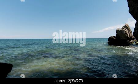 Luftaufnahme von Felsen und sandigen Küsten, Sommer- und Urlaubskonzept. Aktion. Fliegen durch den Steinbogen mit dem endlosen Ozean hinter dem Horizont. Stockfoto