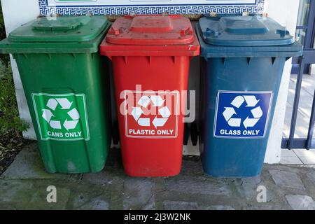 Drei verschiedene farbige Kunststoffbehälter zum Recycling. Grün für Dosen rot für Kunststoff und ein blauer Behälter für Glas. Stockfoto