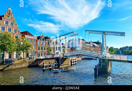 Haarlem, Niederlande - Juni 26. 2020: Blick über den holländischen Wasserkanal auf einer zweistrahligen Zugbrücke (Gravestenenbrug), alte Häuser, blauer Sommerhimmel Stockfoto