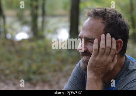 Lächelnder reifer Mann mit der Hand auf dem Gesicht Stockfoto