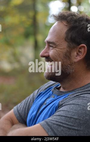 Ein lächelnder Mann, der im Herbst draußen steht Stockfoto