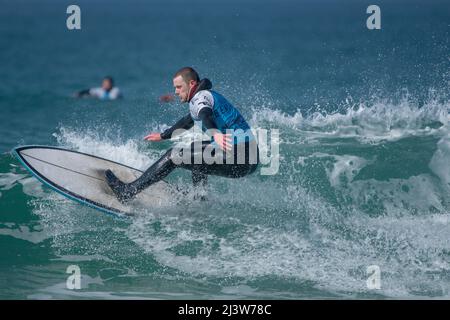 Ein männlicher Surfer, der an einem Surfwettbewerb im britischen Fistral in Newquay in Cornwall teilhat. Stockfoto