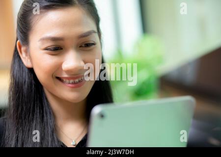 Junge asiatische Geschäftsfrau mit Tablet-Computer arbeiten im Büro, Frau oder Mitarbeiter suchen Tablet mit selbstbewussten, Geschäftsleute arbeiten online, ein Stockfoto