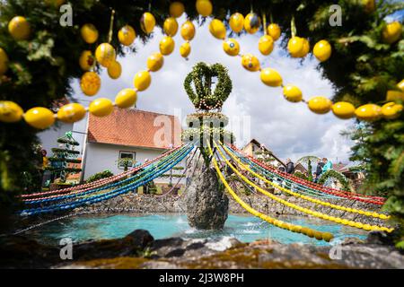 10. April 2022, Bayern, Egloffstein: Wolken ziehen über den größten Osterbrunnen der Fränkischen Schweiz, den Osterbrunnen in Bieberbach, Teil der Gemeinde Egloffstein. Nach einer zweijährigen Pause aufgrund der Pandemie werden verächtliche Brunnen wieder zu bunten Kunstwerken: In der Fränkischen Schweiz wurden am Wochenende die ersten Osterbrunnen mit bemalten Eiern und Girlanden aus Tannenzweigen geschmückt. Foto: Nicolas Armer/dpa Stockfoto