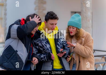 Eine Gruppe von erstaunlichen und attraktiven Freunden schaut sich etwas am Telefon an Stockfoto