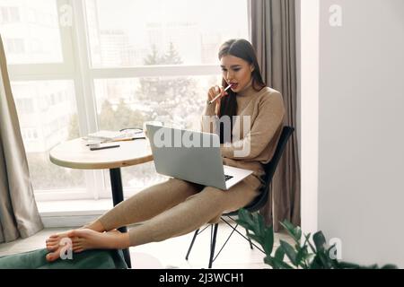 Schöne glückliche Frau, die mit einem Laptop arbeitet. Lächelnde Geschäftsfrau, die den Computer benutzt. Stockfoto