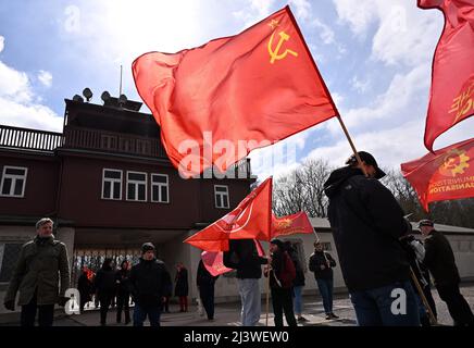 Weimar, Deutschland. 10. April 2022. Die Besucher der Gedenkstätte Buchenwald bei Weimar tragen rote Fahnen, darunter die der ehemaligen Sowjetunion, zum Gedenken an die Befreiung des ehemaligen Nazi-Konzentrationslagers vor 77 Jahren. Zum ersten Mal seit Beginn der Corona-Pandemie werden unter anderem KZ-Überlebende aus Israel, Polen und Rumänien erwartet. Vertreter der Regierungen Russlands und Weißrusslands wurden von der Gedenkstätte abberufen. Quelle: Martin Schutt/dpa/Alamy Live News Stockfoto