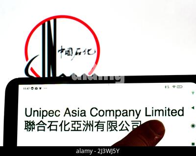 In dieser Abbildung wird das Logo der Unipec Asia Company Limited auf einem Smartphone-Bildschirm mit einem Logo der China Petroleum & Chemical Corporation (Sinopec) im Hintergrund angezeigt Stockfoto