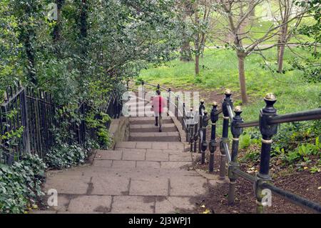 Sie blicken auf eine Frau in roter Jacke, die die Treppe im Thompson's Park, Romilly Road Cardiff, hinuntergeht Stockfoto