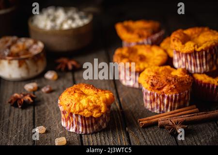 Süße hausgemachte Hüttenkäse-Muffins mit Kürbis auf dunklem Holzhintergrund Stockfoto