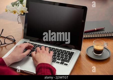 Leerer Laptop-Computerbildschirm, Frau arbeitet im Heimbüro, offenes Notebook auf Holztisch, leeres schwarzes Display, Kopierplatz, Stockfoto