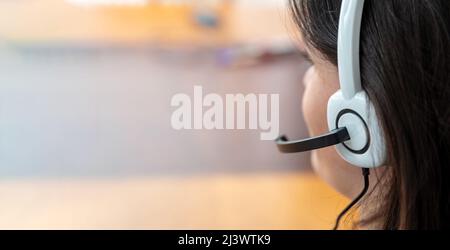 Call Center, Home Office, Kundendienst, Helpdesk-Konzept. Frau mit Headset spricht am Telefon, Nahaufnahme von hinten. Speicherplatz kopieren Stockfoto