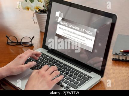 Lösegeld Ware, Cyber-Angriff Konzept. Warnmeldung auf einem Computerbildschirm. Frau, die mit einem Laptop arbeitet. Büro Business Holz Tisch Hintergrund. Stockfoto