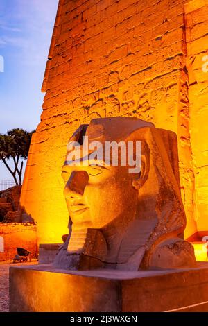 Nahaufnahme der Statue des Pharao Ramses II Kopf vor dem Mast des Luxor-Tempelkomplexes in der Nacht, Luxor, Ägypten. Stockfoto