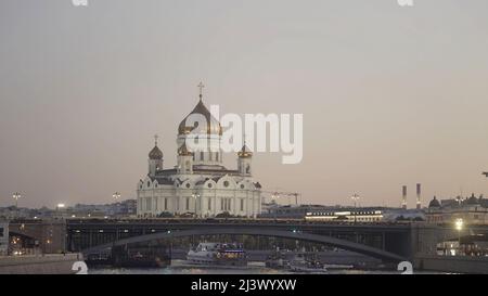 Luftaufnahme des schönen alten Kathedralengebäudes und des Flusses Moskau im Hintergrund des Sonnenuntergangs. Aktion. Große Kirchen mit goldenen Kuppeln und der Brücke Stockfoto