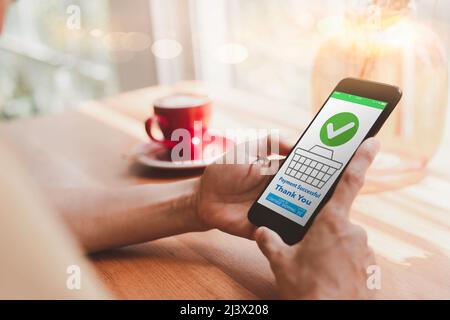 Nahaufnahme einer Frau, die ein Mobiltelefon nutzt, um online einzukaufen. Frauen kaufen gerne online ein. Auf dem mobilen Bildschirm wird angezeigt, dass die Zahlung abgeschlossen ist. Frauen freuen sich darüber Stockfoto