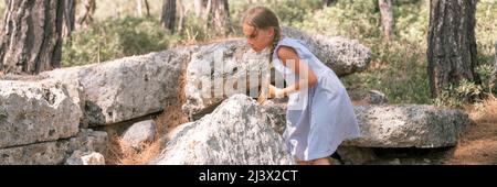 Junge Mädchen Reisende von acht Jahren reisen und erkunden die alten Ausgrabungen der Ruinen der alten lykischen Stadt Phaselis in der Türkei in Summe Stockfoto