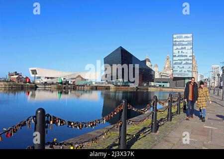 Junges Paar, das am Strand neben dem Canning Dock entlang geht - mit Museum of Liverpool, Open Eye Gallery & RIBA Offices, Waterfront, Großbritannien Stockfoto