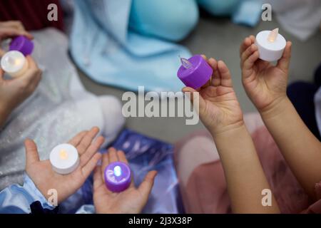 Elektronische Kerze in der Hand eines kleinen Kindes. Ein Kinderfuß. Die Details Stockfoto