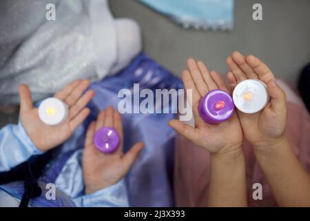 Elektronische Kerze in der Hand eines kleinen Kindes. Ein Kinderfuß. Die Details Stockfoto