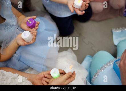 Elektronische Kerze in der Hand eines kleinen Kindes. Ein Kinderfuß. Die Details Stockfoto