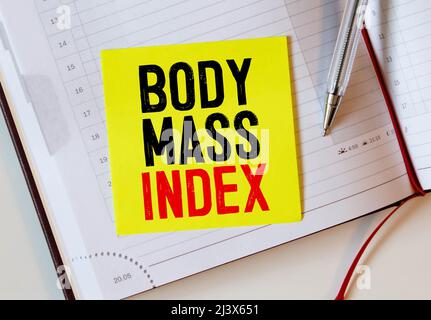 Body Mass Indextext auf Notizbuch mit leckerem grünen Apfel, Maßband, Spektakel, einer Flasche Mineralwasser und Bodybuilding-Werkzeugen auf Holzrücken Stockfoto