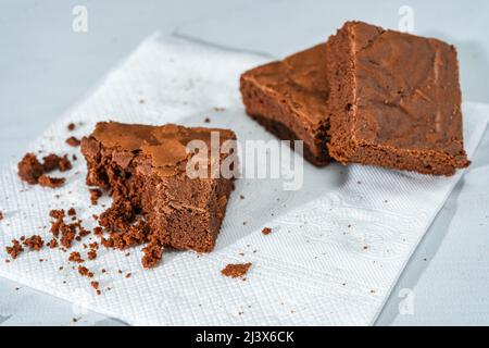 Auf einem weißen Teller auf einem Marmortisch stehen Schokoladenwürfel. Stockfoto