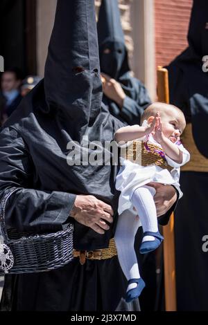 Sevilla, Spanien. 10. April 2022. Ein Büßer der Bruderschaft namens ''La Borriquita'' trägt ein Baby während seiner Parade zur Kathedrale am Palmsonntag, ''Domingo de Ramos'' auf Spanisch (Bildquelle: © Daniel Gonzalez Acuna/ZUMA Press Wire) Bildquelle: ZUMA Press, Inc./Alamy Live News Stockfoto