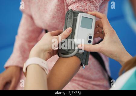 Arzt überprüft den Blutdruck der Frau mit dem Holter-Monitor Stockfoto