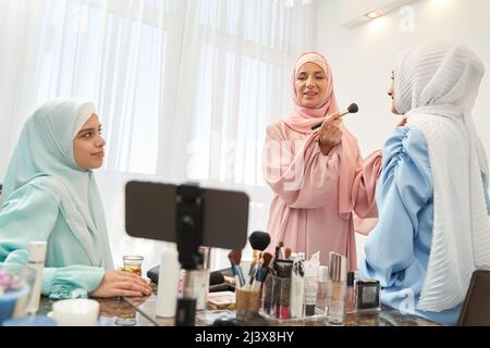 Selbstbewusste muslimische Frau, die online an Make-up arbeitet Stockfoto