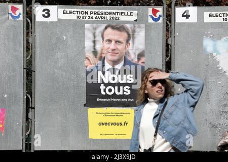 Paris, Frankreich. 10. April 2022. Ein Bewohner kommt an einem Wahlplakat vorbei, auf dem der aktuelle französische Präsident Emmanuel Macron bei der ersten Runde der Präsidentschaftswahlen am Sonntag, dem 10. April 2022, in Paris, Frankreich, zu sehen ist. Französische Bürger kamen nach einer Kampagne, die von der russischen Invasion in die Ukraine überschattet wurde, zu den Wahlen. Foto von Maya Vidon-White/UPI Credit: UPI/Alamy Live News Stockfoto