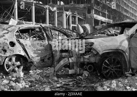 Nach der Shell von Zivilisten bombardiert Stadt Schaden Auto. 2022 Russische Invasion der Ukraine Krieg zerrissene Stadt zerstört Auto brennen aus. Bombe Angriff Russland Krieg Stockfoto