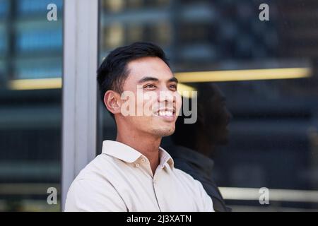 Porträt eines jungen südostasiatischen Geschäftsmannes vor einem Bürofenster Stockfoto