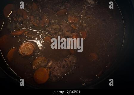 Geschmorte Rinderbacken in Rotweinsauce im gusseisernen holländischen Ofen. Langsam gekochter Fleischeintopf. Stockfoto