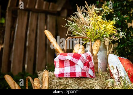 Strohkorb mit einem Baguette auf einem Strohballen. Stockfoto