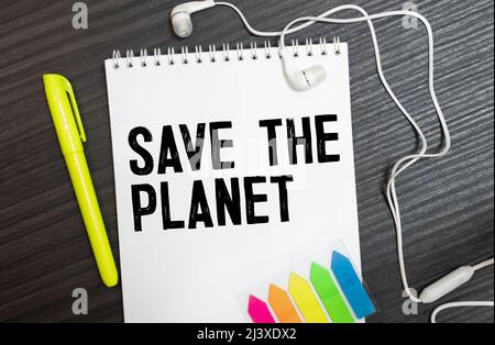 Closeup Gelbe Haftnotiz Fügen Sie sie in ein Notizbuch ein, um einen Termin zu vereinbaren. Die Worte Save the Planet, die auf einem weißen Notizbuch geschrieben wurden, erinnern an einen Impor Stockfoto