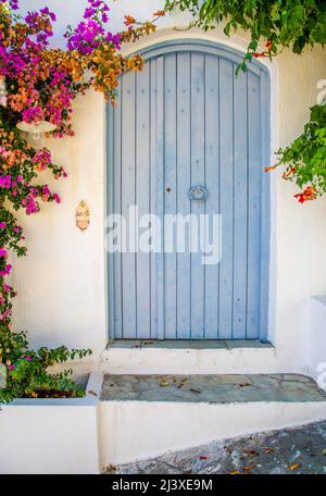 Blaue Tür in einer weißen Wand mit Bouganvillea auf der Insel Alonnisos auf den griechischen Sporaden Stockfoto