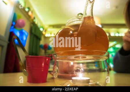 Sanddorntee mit Minze in einer durchsichtigen Glas-Teekane. Stockfoto