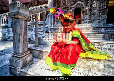 Ein junges Mädchen, das auf ihrem Handy gesehen wurde, nachdem es an der Kumari Puja im Adyapith-Tempel teilgenommen hatte. Kumari Puja ist eine indische hinduistische Tradition, die hauptsächlich während der Durga Puja/Basanti Puja/Navratri nach dem hinduistischen Kalender gefeiert wird. Kumari beschreibt tatsächlich ein junges jungfräuliches Mädchen im Alter von 1 bis 16 Jahren, das nach der hinduistischen Mythologie während des Übergangs von Ashtami/Navami Tithiti von Durga Puja/Navratri verehrt wird. Es wird angenommen, dass Kumari Puja den Betern und auch dem kleinen Mädchen viele Segnungen gewährt. Anhänger glauben, dass es alle Barrieren überwinden wird, Gefahren für die l Stockfoto