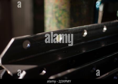 Stahlteil. Dickes Metall. Gebohrte Löcher im Werkstück. Details der Metallwerkstatt. Hintergrund eines Teils der Struktur. Befestigungselemente für schwere Lasten. Stockfoto