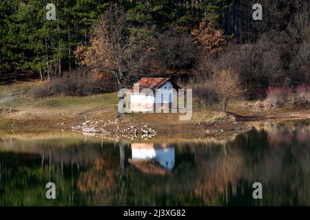 Schöne Herbst Berglandschaft und Reflexion im Wasser der Kapelle "St. Petka' (St. Paraskeva) und Waldbäumen am Ufer des Incredi Stockfoto
