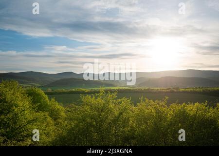 Schöne grüne Berglandschaft mit Sonne und Sonnenstrahlen über den Hügeln. Stockfoto