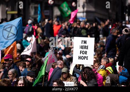 London, Großbritannien. 09. April 2022. Während der Demonstration werden Demonstranten mit Plakaten und Flaggen bei einem Sit-in im Oxford Circus gesehen. Die Protestgruppe „Extinction Rebellion“ organisierte im Zentrum von London einen Protest, der alle aufforderte, gemeinsam für den letzten Schub des Plans zur Beendigung der fossilen Brennstoffe zu stehen. Sie glauben, dass die Abhängigkeit der Menschen von fossilen Brennstoffen Kriege finanziert, die Lebenshaltungskosten schürt und zum Zusammenbruch des Klimas führt. Aus diesem Grund fordern sie ein sofortiges Ende aller Investitionen in neue fossile Brennstoffe. Kredit: SOPA Images Limited/Alamy Live Nachrichten Stockfoto