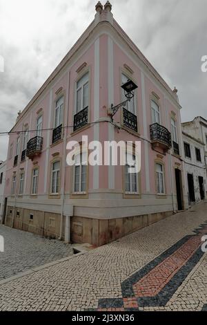 Pinkfarbene Fassade – neoklassizistische Gebäudeecke – gepflasterte Infante de Sagres Street. Lagos-Portugal-207 Stockfoto