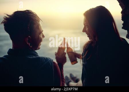 Zu einem wohlverdienten Getränk. Kurzer Schuss eines liebevollen jungen Paares, das auf einem Berg mit Bier rötet. Stockfoto