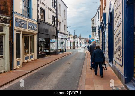 Ein Paar geht auf einem Bürgersteig entlang der Middlegate in Penrith, Cumbria, Großbritannien Stockfoto