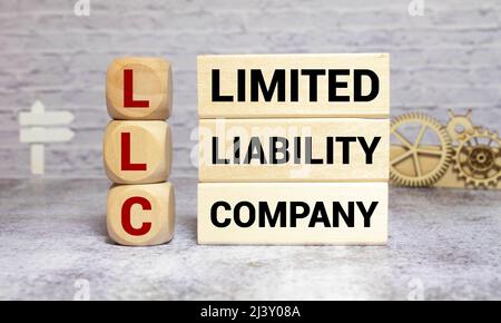 LLC Limited Liability Company auf einem Holzwürfel auf einem Schreibtisch geschrieben. Stockfoto