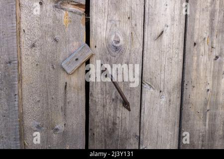 Geschlossene Tür mit eisernem Griff. Tür mit Holzverschluss geschlossen Stockfoto